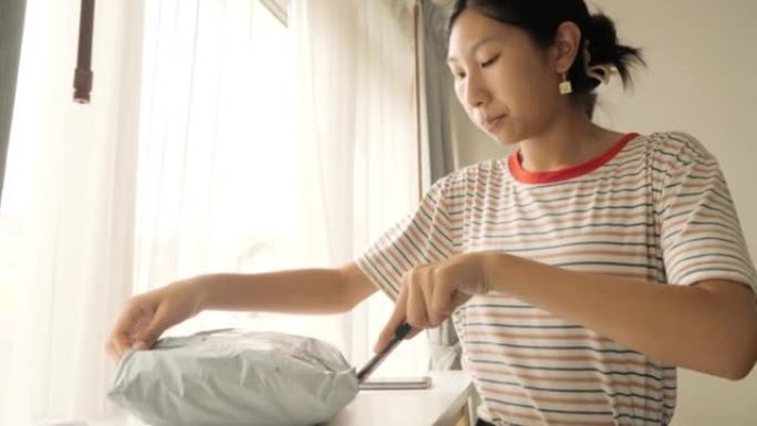 亚洲少女拆箱一些从网上购物中购买的商品，生活方式概念。