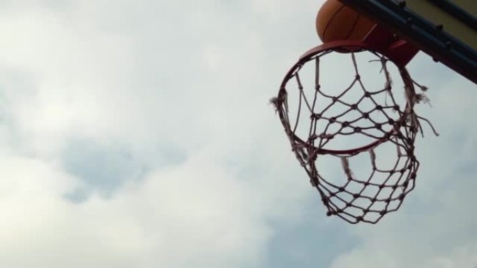 篮球橙色球错过篮筐在多云的天空前慢动作未击中目标。未能得分倒霉的射门从篮筐篮板反弹