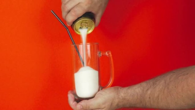 用吸管将一罐苏打水中的糖倒入玻璃杯中。