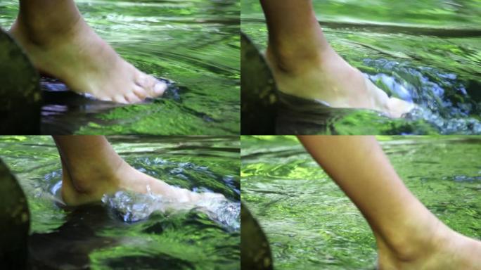 赤脚男孩用清澈的水和田园诗般的漂浮小溪在水中冷却他的脚在夏天展示了户外徒步旅行，在平静的小溪与家庭户