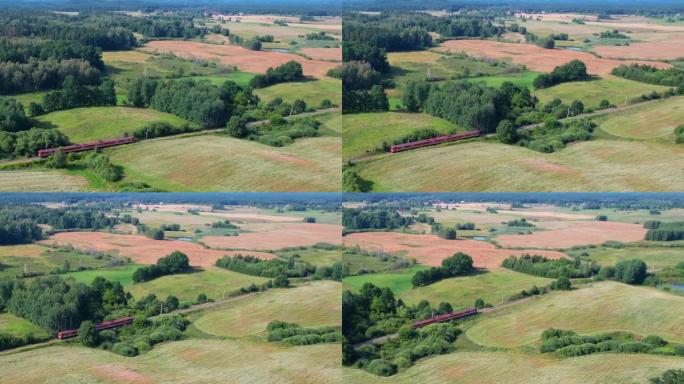铁路上的红色火车。波兰公共交通基础设施的旅客列车鸟瞰图景观。客运电动火车穿过美丽的欧洲乡村的农田。