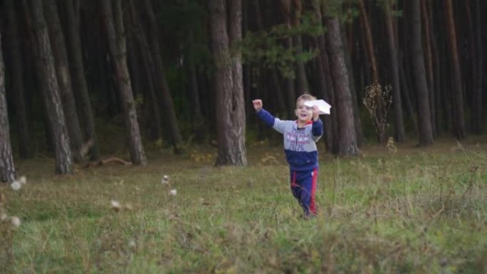 一个小男孩玩玩具飞机，在公园里奔跑。自由梦想概念。