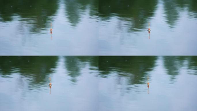 白色和橙色的钓鱼浮子漂浮在河里。阴天静止的水面上不动的漂浮。