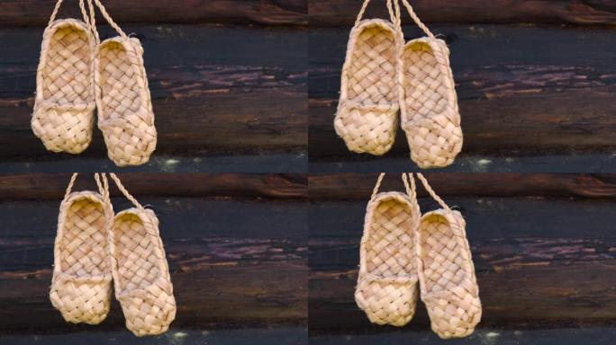 乡村乡村概念。古董手工乡村鞋-韧皮鞋。一双挂在木木墙背景上的韧皮鞋。