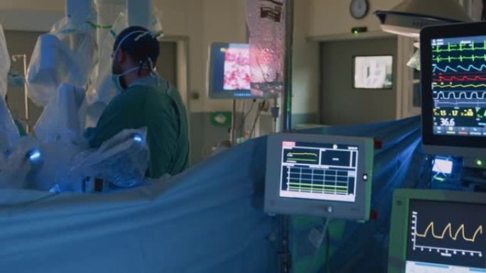 护士在手术期间看着监视器，而外科医生切除肿瘤。现代医疗设备。外科医生助理护士