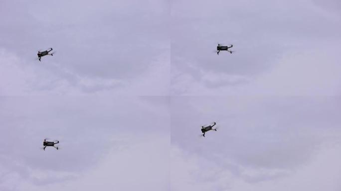 现代民用四轴飞行器无人机在多云的天空中机动，从地面看