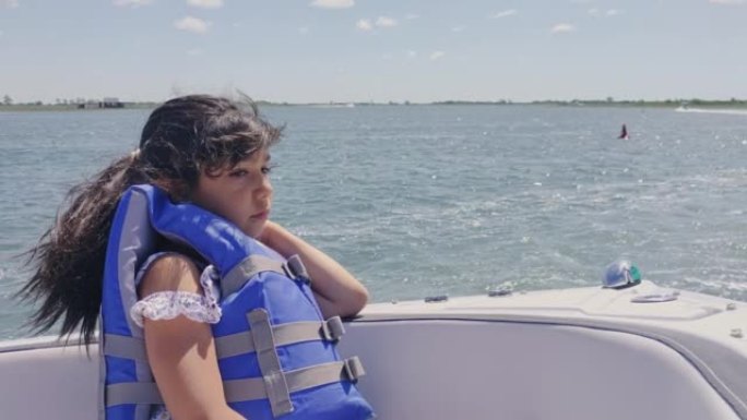 穿着救生衣的小女孩坐在船上，享受着家庭旅行。纽约海滨。
