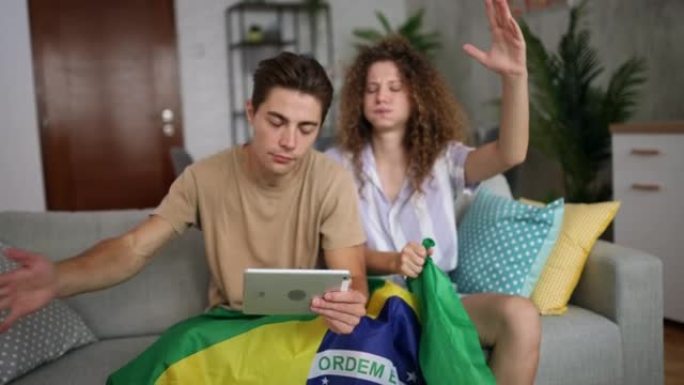 年轻夫妇在平板电脑上观看体育比赛并扎根巴西
