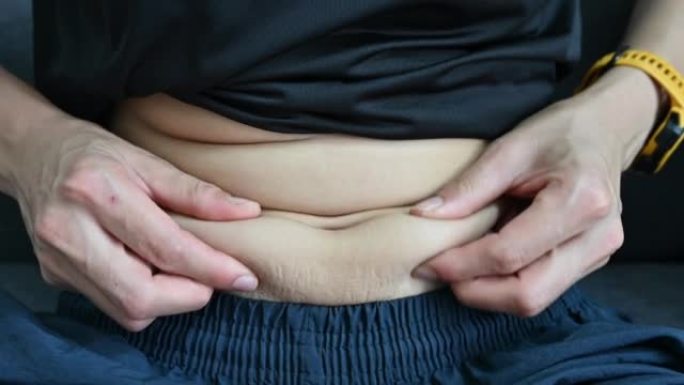 女人触摸和玩她肥胖的肚子的特写镜头。