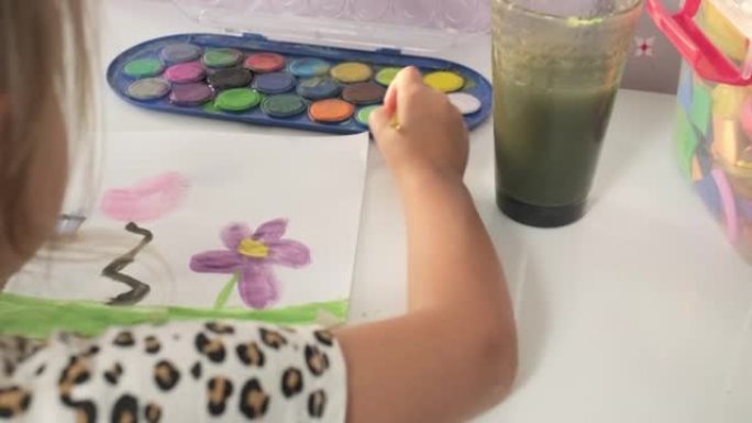 才华横溢的创意儿童女孩女艺术家用手在纸上画画，用手指画笔在家里的桌子上画五颜六色的孩子画。画家创造抽
