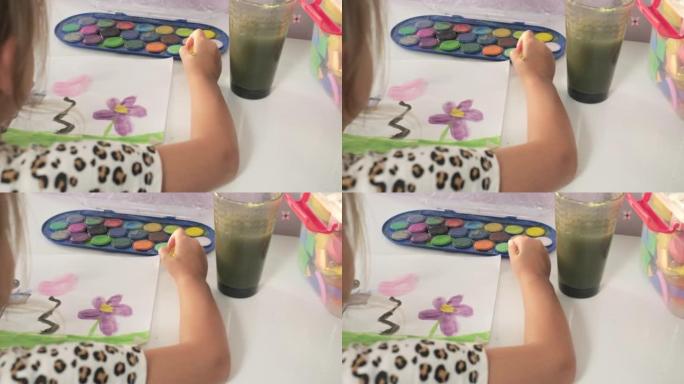 才华横溢的创意儿童女孩女艺术家用手在纸上画画，用手指画笔在家里的桌子上画五颜六色的孩子画。画家创造抽
