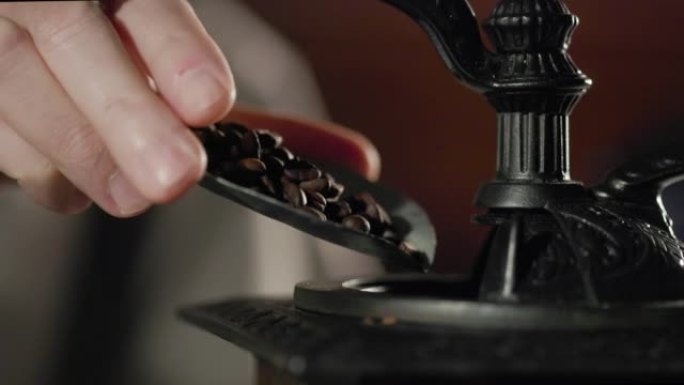将少量咖啡豆从平衡秤的锅中倒入老式研磨机中。