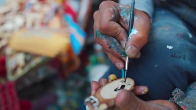 印度喜马偕尔邦马纳利Mall Road的街道上，街头画家亲手画木制钥匙扣的特写镜头。城市生活方式，街