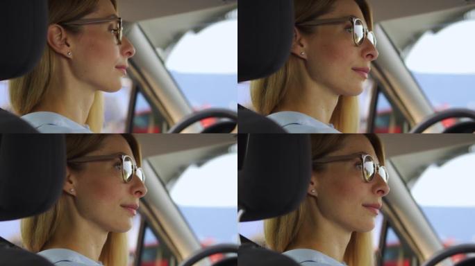 细心的金发女司机戴着时尚的眼镜环顾四周，让汽车和行人经过，等待红绿灯切换，小心遵守交通规则，特写