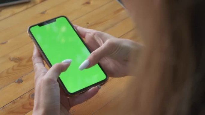 Womans hands hold smartphone which green screen