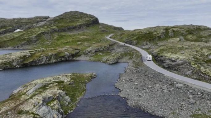 穿过挪威高地的公路上有红船的露营车的风景鸟瞰图