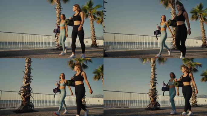 肖像两个女人穿着运动服，拿着瑜伽垫，准备户外训练，在做瑜伽之后或之前，选择锻炼的地方，去健身房，享受