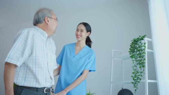 亚洲老年男性患者与护理人员一起进行物理治疗。有吸引力的专业护理女性帮助和支持老年成熟男性练习与沃克在
