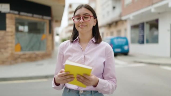 年轻的西班牙裔妇女在街上微笑着自信的拥抱书