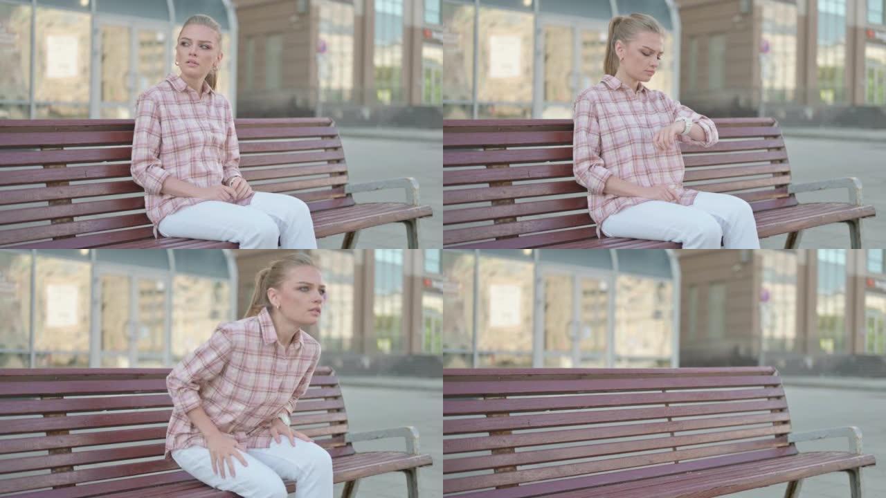 年轻女子坐在户外长凳上后站着离开
