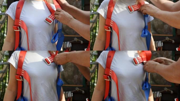 安全教练为登山者女孩准备攀登攀岩墙的设备