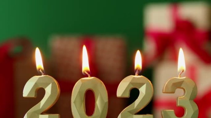 点燃的蜡烛是2023年的象征。圣诞bokeh背景。背景中的加兰。新年快乐，圣诞快乐。蜡烛2023燃烧