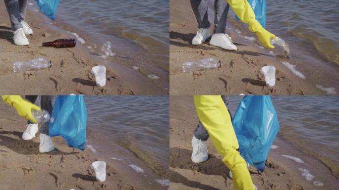 女人捡起散落在沙子上的塑料袋和瓶子