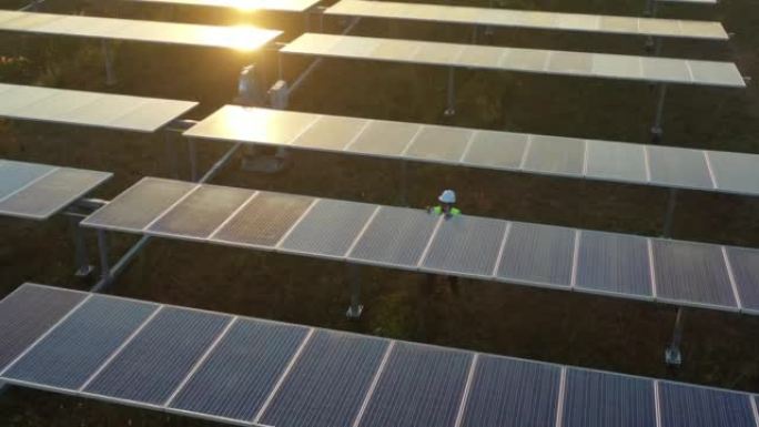 空中无人机视图技术人员在太阳能电池板排之间行走