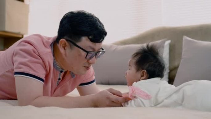 4K，亚洲爸爸，穿着一件粉红色的衬衫，爸爸撒谎，和女儿一起玩耍，珍爱着，一个年轻的女孩难以置信地深情