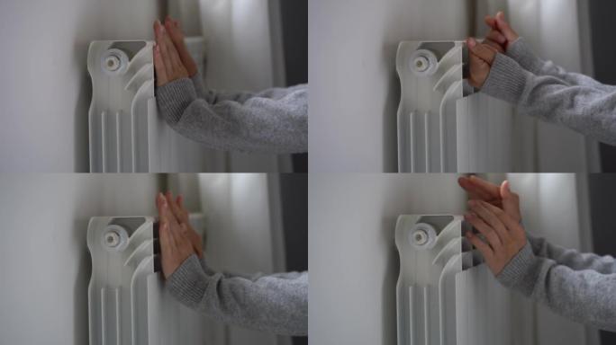 女人变冷，试图感受温暖，把手放在运动衫里，放在公寓里的暖气片上