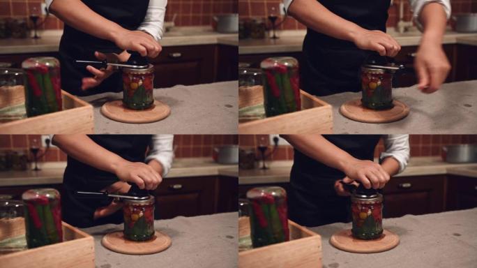 使用特殊接缝钥匙seamer的家庭主妇特写镜头，用新鲜罐装的樱桃番茄关闭罐子上的盖子