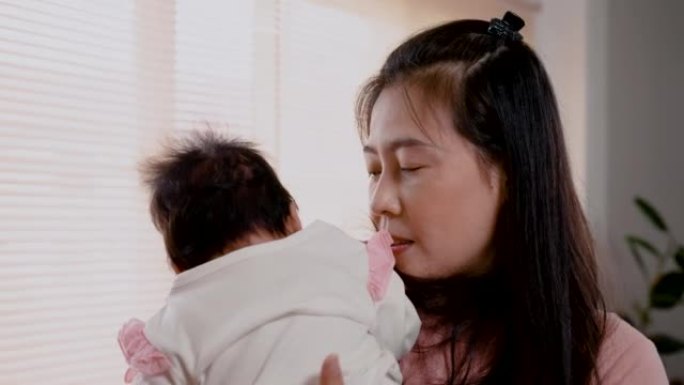 4K，关闭亚洲妇女抱着她3个月大的女婴，并谈论让婴儿在下午在卧室睡觉的好处。单身母亲正在照顾新生婴儿