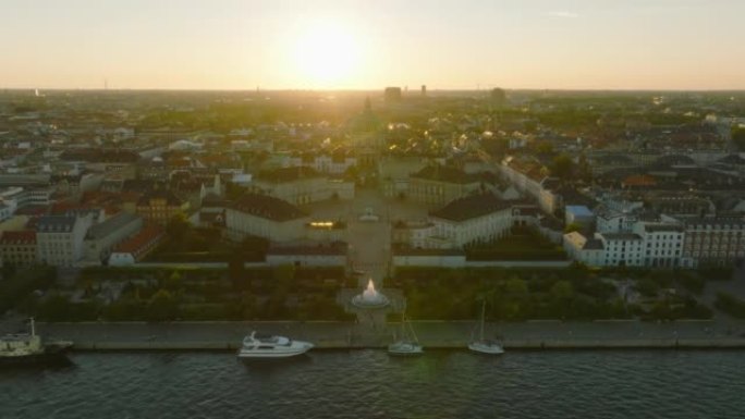 皇家阿玛林堡宫的空中下降镜头和弗雷德里克·柯克穹顶的剪影，对抗夕阳。丹麦哥本哈根