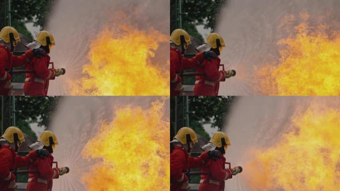 消防员使用消防水带扑灭燃烧的大火。
