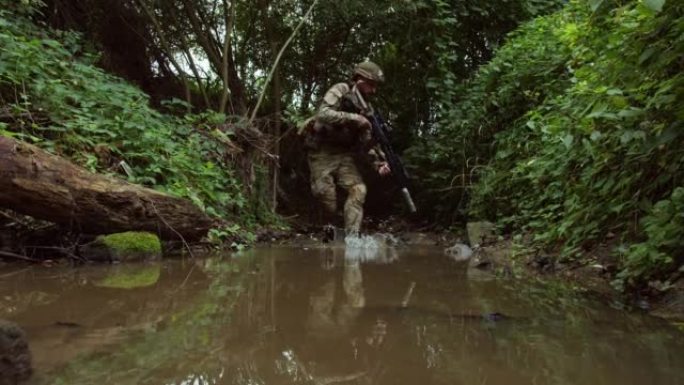 北约士兵在丛林中沿着森林中的河流战术地散步