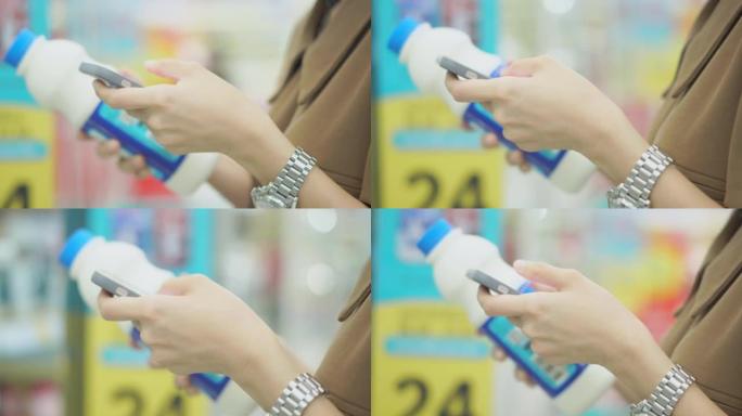 戴着口罩的亚洲妇女在超市用智能手机买牛奶