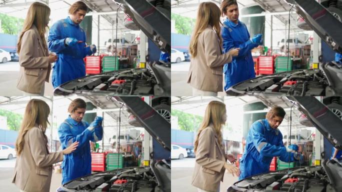 专业的车辆保养男人教美女检查机油的水平。拉动润滑油测量杆，并在车库中显示给客户。汽车维修服务