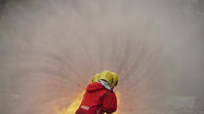 消防员使用消防水带扑灭燃烧的大火。