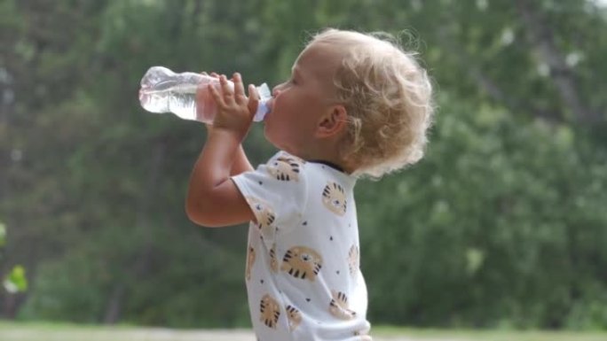 夏天，孩子从公园的婴儿奶瓶中喝水，1.5岁的蹒跚学步的孩子在户外自然。