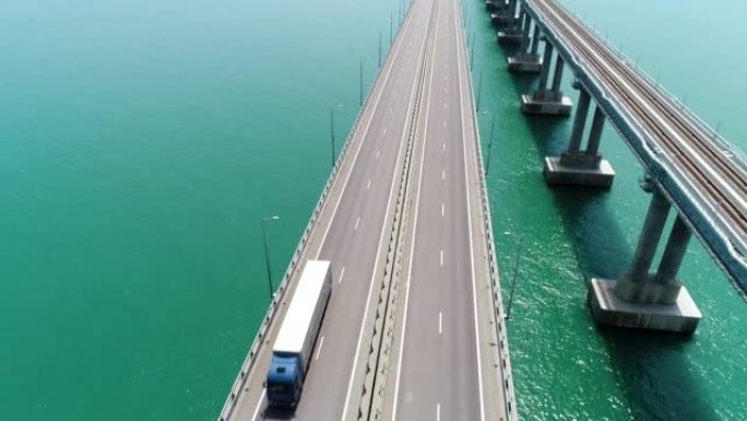用移动的车辆在新的白色桥上方飞行。行动。令人叹为观止的海洋景观，在蓝色平静的水面上有一座长桥。