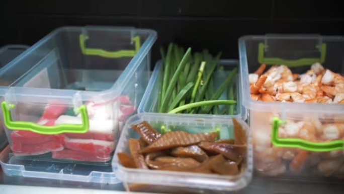 食品。俯视图。特写。塑料容器中的海鲜。蟹棒、黄瓜切片、鱼、鳗鱼、煮虾。制作寿司的半成品。烹饪。