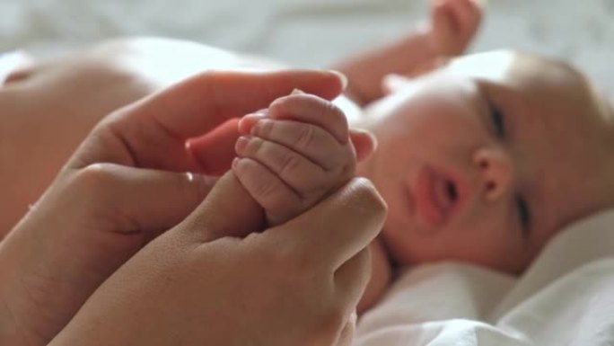 婴儿手放在母亲的手中，放在她的手掌上。快乐的父母抱着刚出生的婴儿小手指，近距离接触。生育，家庭，生育