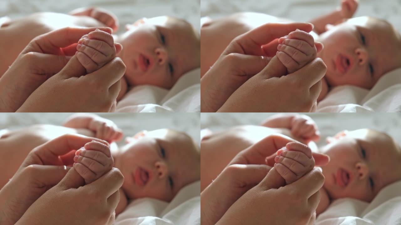 婴儿手放在母亲的手中，放在她的手掌上。快乐的父母抱着刚出生的婴儿小手指，近距离接触。生育，家庭，生育