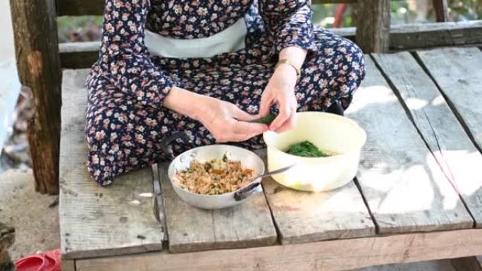 一位高级妇女正在包裹叶子，用米饭塞满藤叶