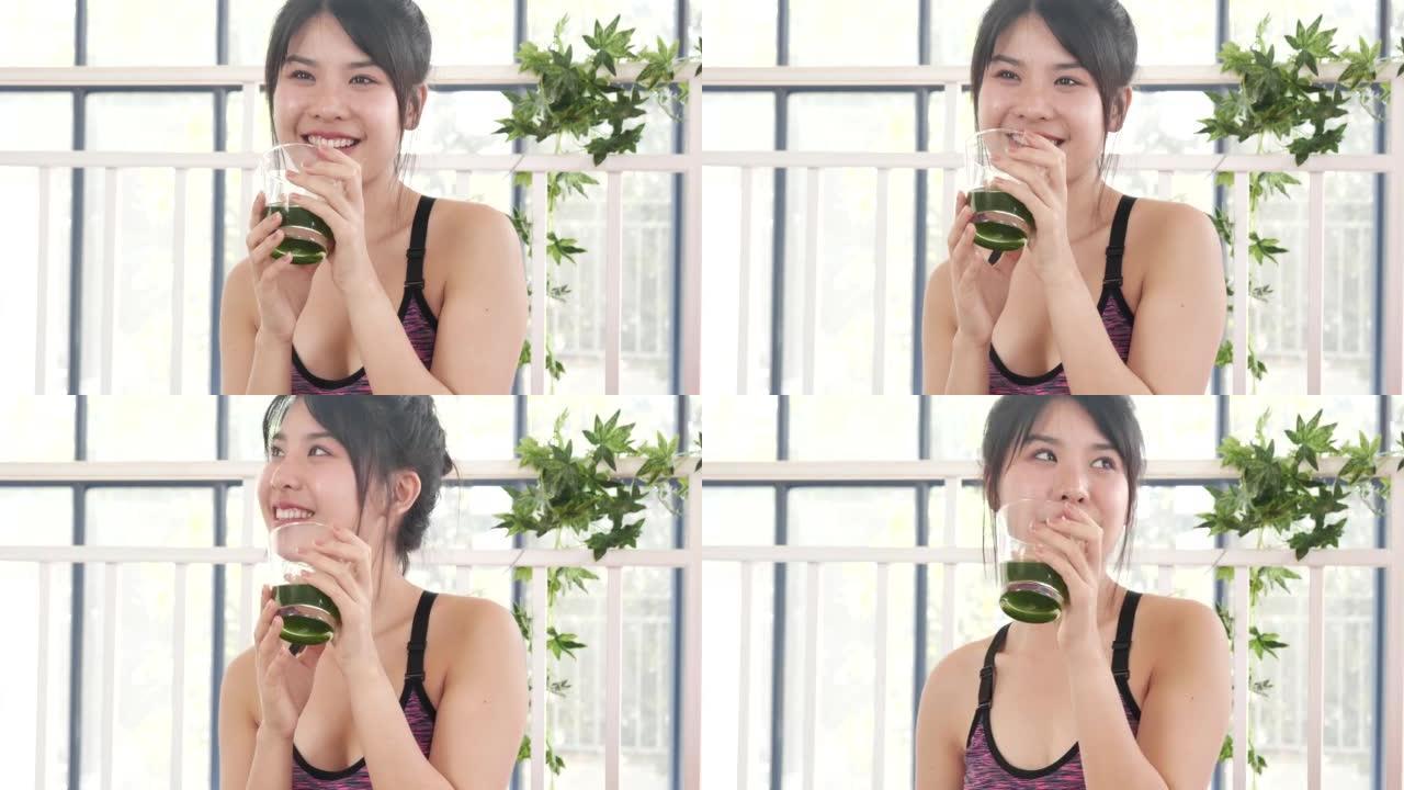 女人双手握着冰沙排毒绿汁新鲜水果清凉饮用。亚洲女性微笑着笑着喝素食蔬菜清凉健康饮料。女性倒芹菜汁饮料