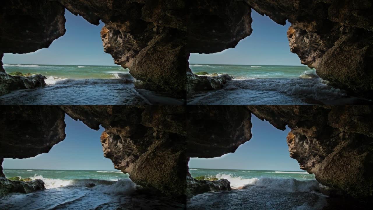 冲浪线上的一个石窟，背景是蓝天和天际线。用三脚架拍摄的长镜头