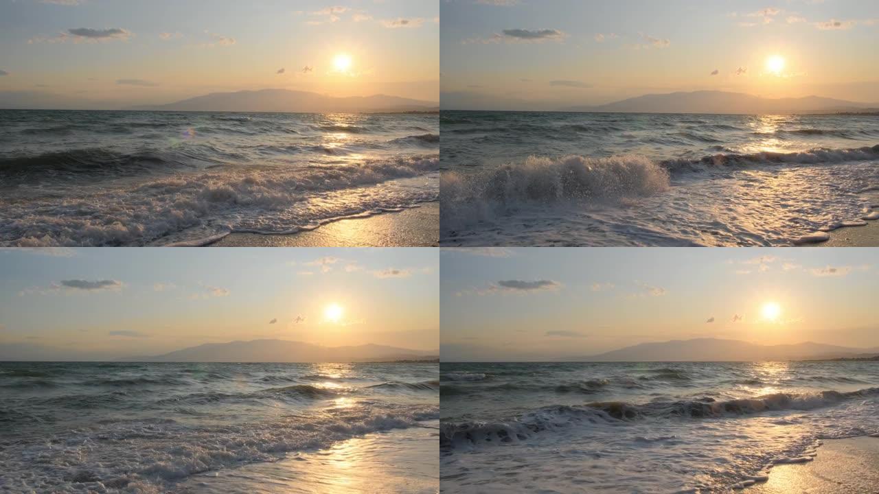 平静的海面上令人惊叹的美丽日出。黄色的太阳升起在海洋和山脉之上，太阳路径在水上。阳光和太阳光线反射在