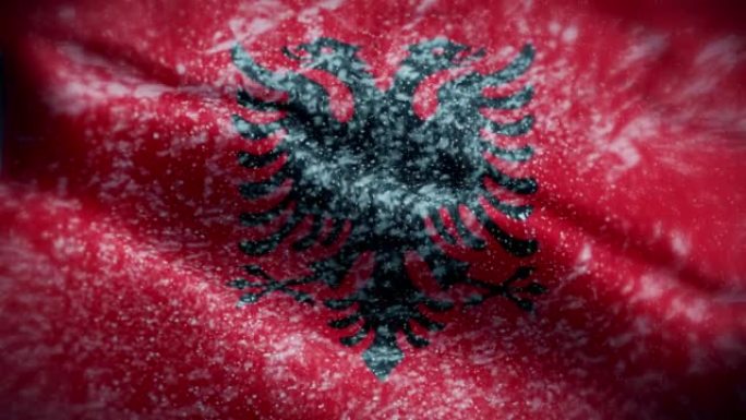 4K暴风雪/雪在阿尔巴尼亚国旗股票视频。冷淡的阿尔巴尼亚国旗。旋转/旋转的冰晶。雪花掠过阿尔巴尼亚国