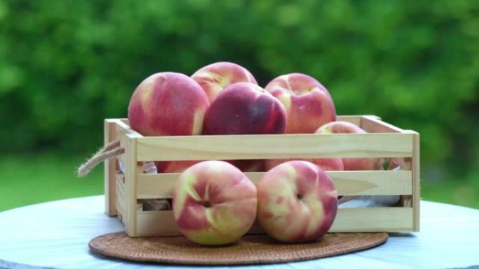 新鲜的桃子，在模糊的绿色背景上切成薄片，桃子水果放在花园木桌上的木篮中。