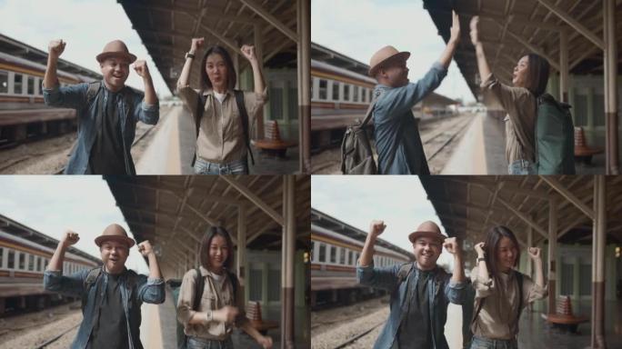快乐的亚洲帅哥和美女背包客戴着帽子和背包说嗨运动和团队合作手在火车站看起来很快乐，一起旅行度假的概念